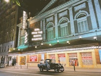 a car is parked in front of a large building at night